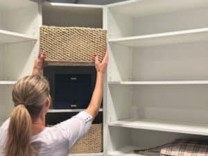 Professional organizer putting bins in a closet