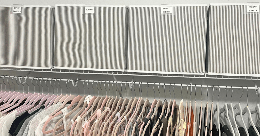 Striped grey and white fabric organizing bins on top of a wire shelf in a closet