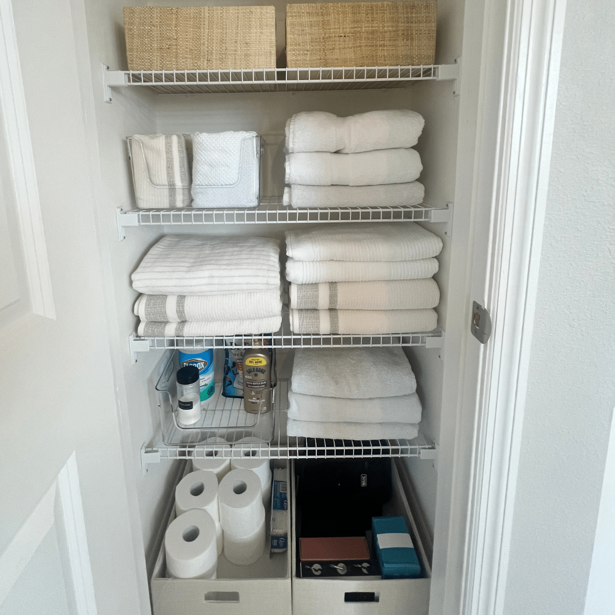 Organized linen closet with neatly folded towels and baskets to hold toiletries