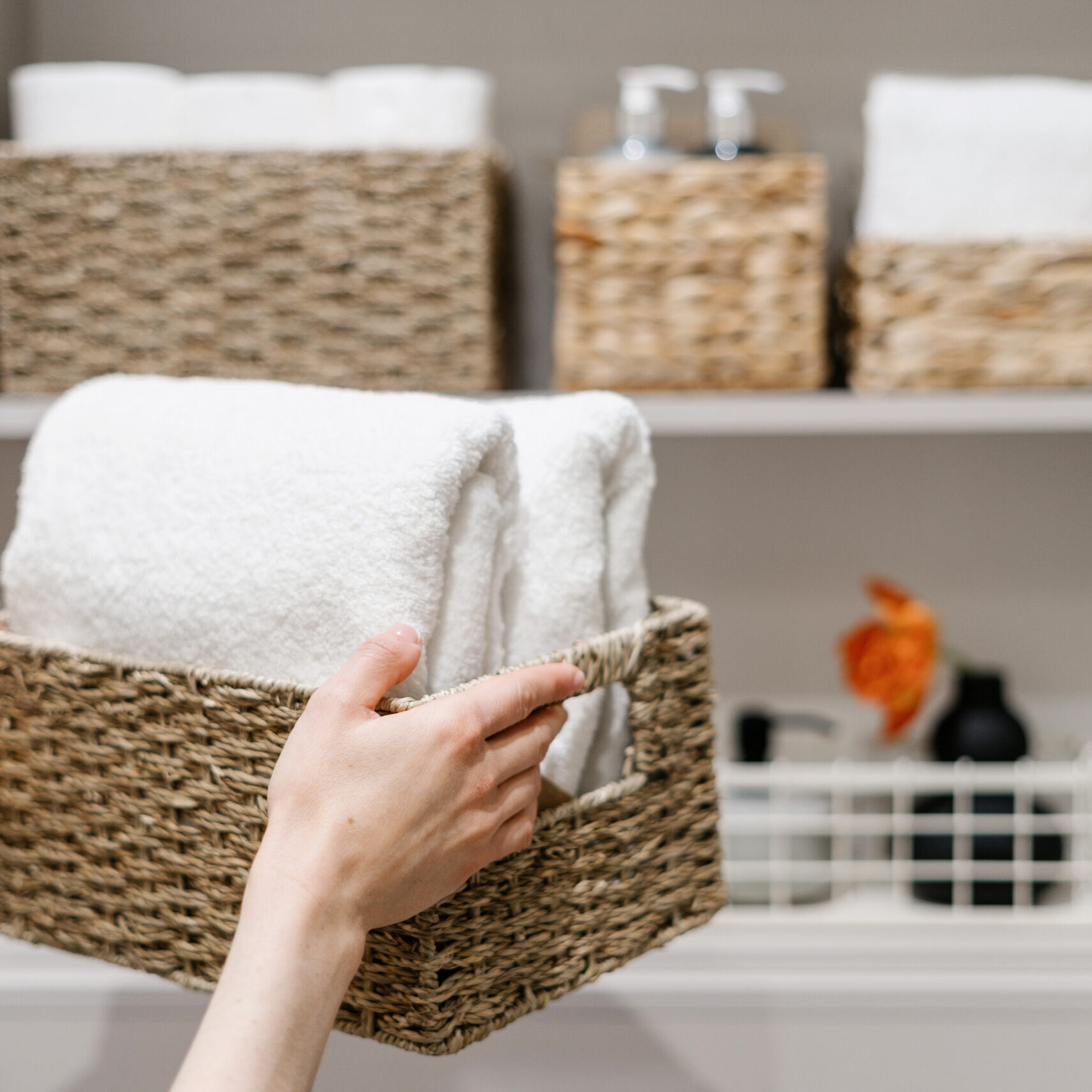 Organization of space in the bathroom cabinet organizing hand towels with seagrass baskets